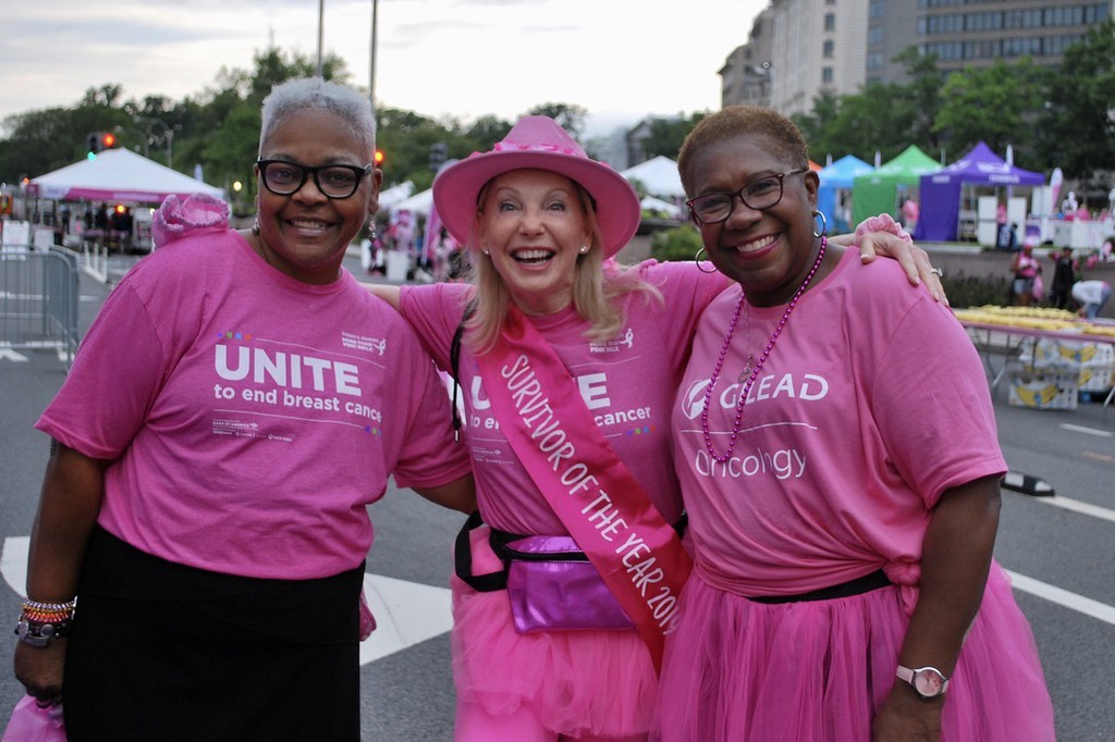 Three women at a Komen event with their arms around each others' shoulders