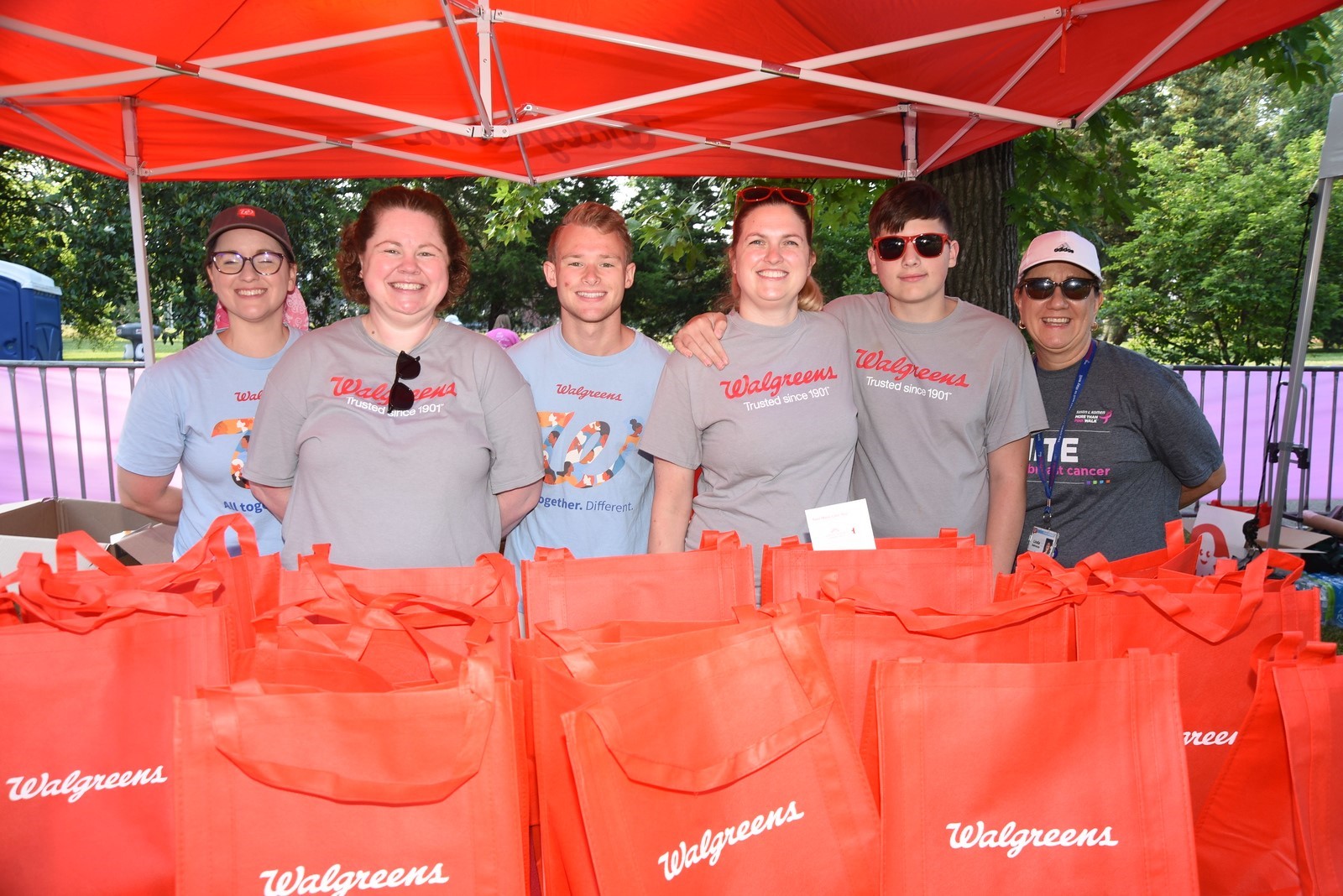 Walgreen's team members at a Komen event posing in front of numerous Walgreens shopping tote bags