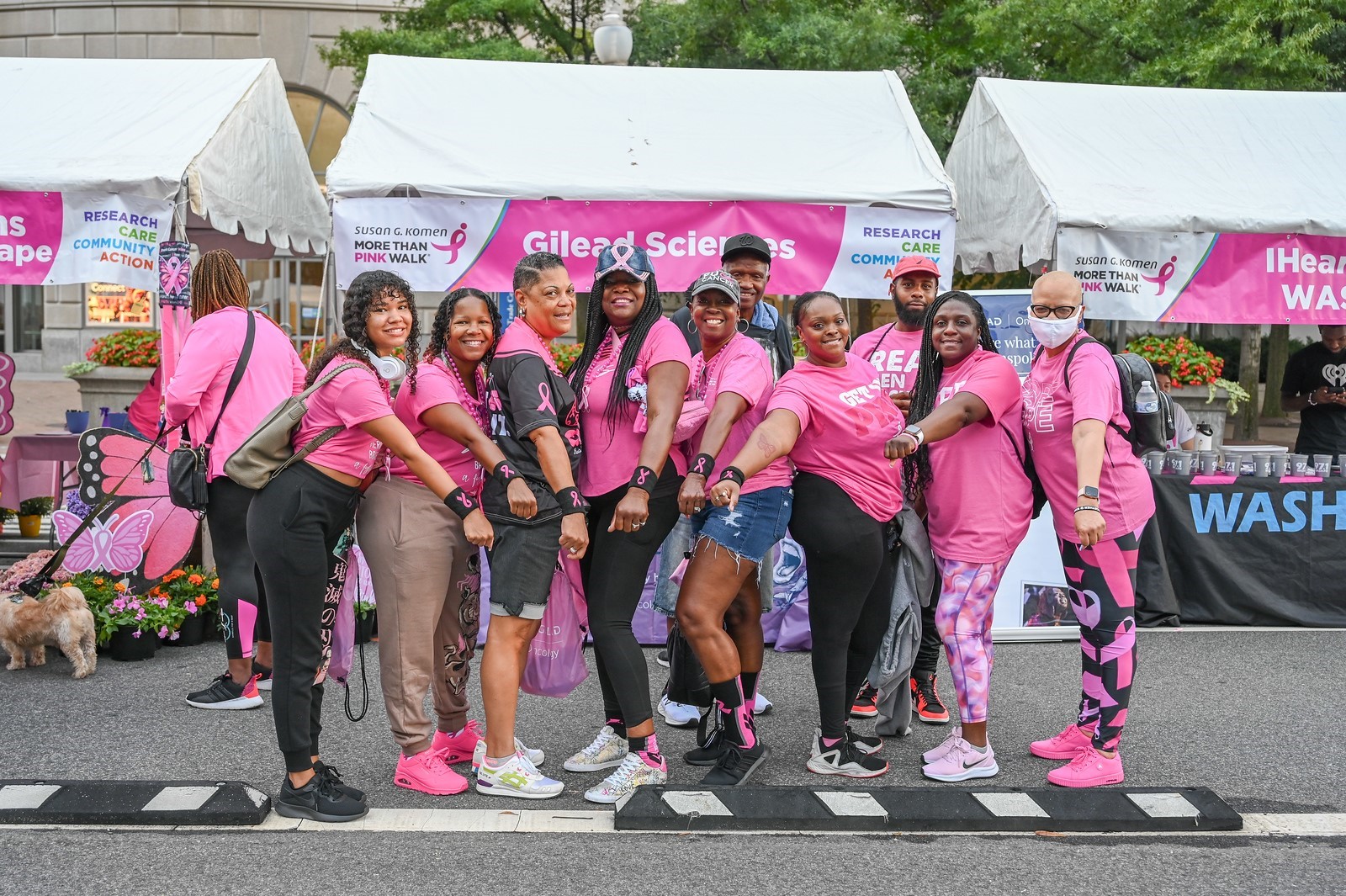 Komen event team members posing with their fists out, showcasing pink ribbon sweatbands on their wrists