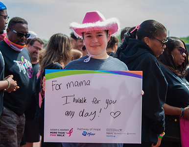 Woman in a pink cowboy hat holding a sign for Mama