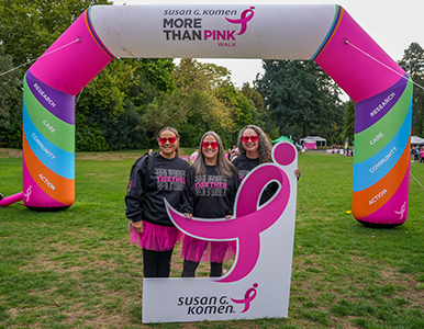 Seattle More Than Walk Women posing under arch with Pink Ribbon Logo sign
